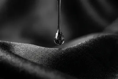 Goutte d'huile capillaire sur un tissu en soie symbolisant le soin capillaire