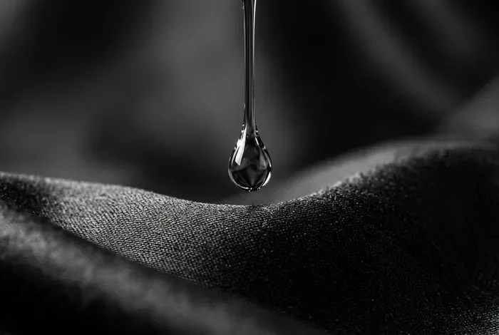 Goutte d'huile capillaire sur un tissu en soie symbolisant le soin capillaire