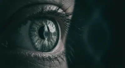 Gros plan d'un œil reflétant une hélice d'ADN, illustrant l'origine génétique du syndrome CANVAS.