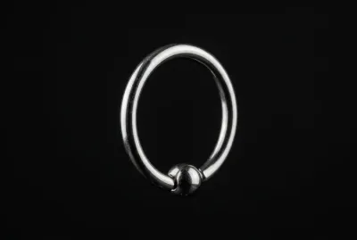 Anneau de piercing en acier chirurgical sur fond noir minimaliste