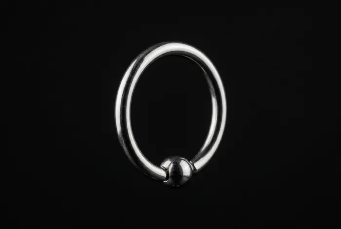 Anneau de piercing en acier chirurgical sur fond noir minimaliste