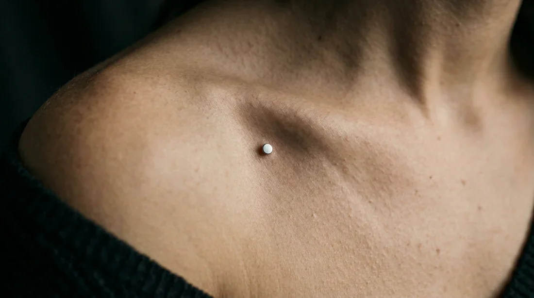 Le piercing microdermal sous un angle artistique Gros plan élégant sur un piercing microdermal au niveau de la clavicule avec un éclairage dramatique