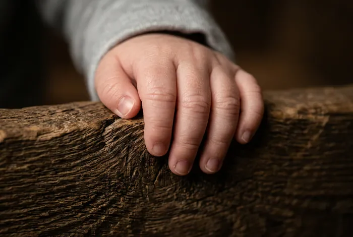 Gros plan sur les mains d'un bébé qui s'agrippe pour se mettre debout.