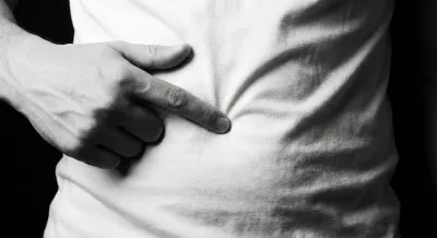 Gros plan d'une main touchant délicatement la zone du nombril.