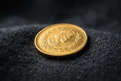 Image minimaliste d'une pièce dorée sur un tissu texturé pour illustrer l'aide financière.