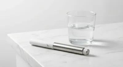 Gros plan minimaliste d'un stylo injecteur sur une surface en marbre, illustrant le traitement Trulicity.